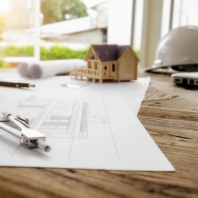 Small model home and blue prints representing new build construction services in Tennessee